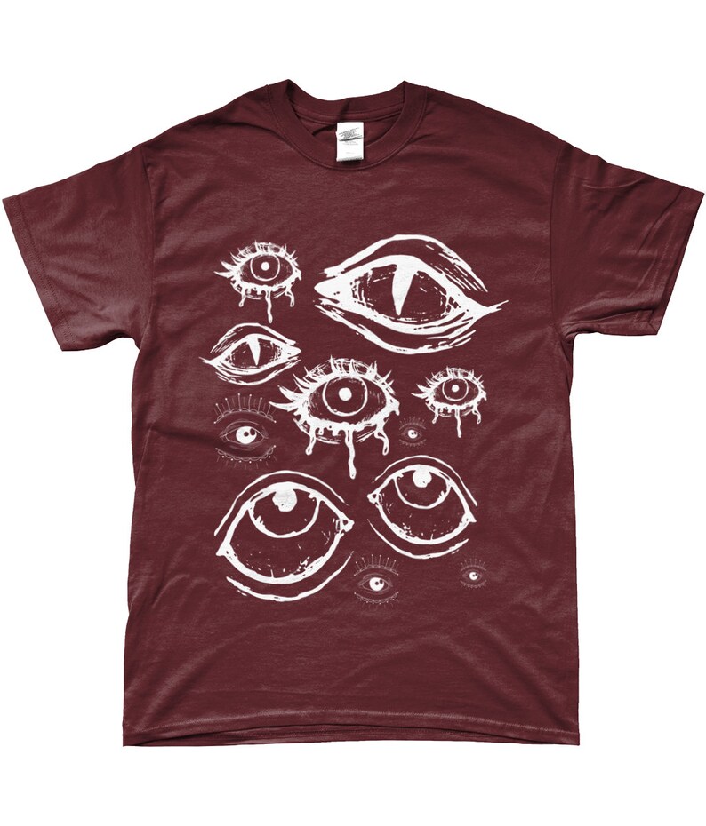 May include: A maroon t-shirt with a white graphic print of multiple stylized eyes. The eyes are drawn in a dripping, abstract style.