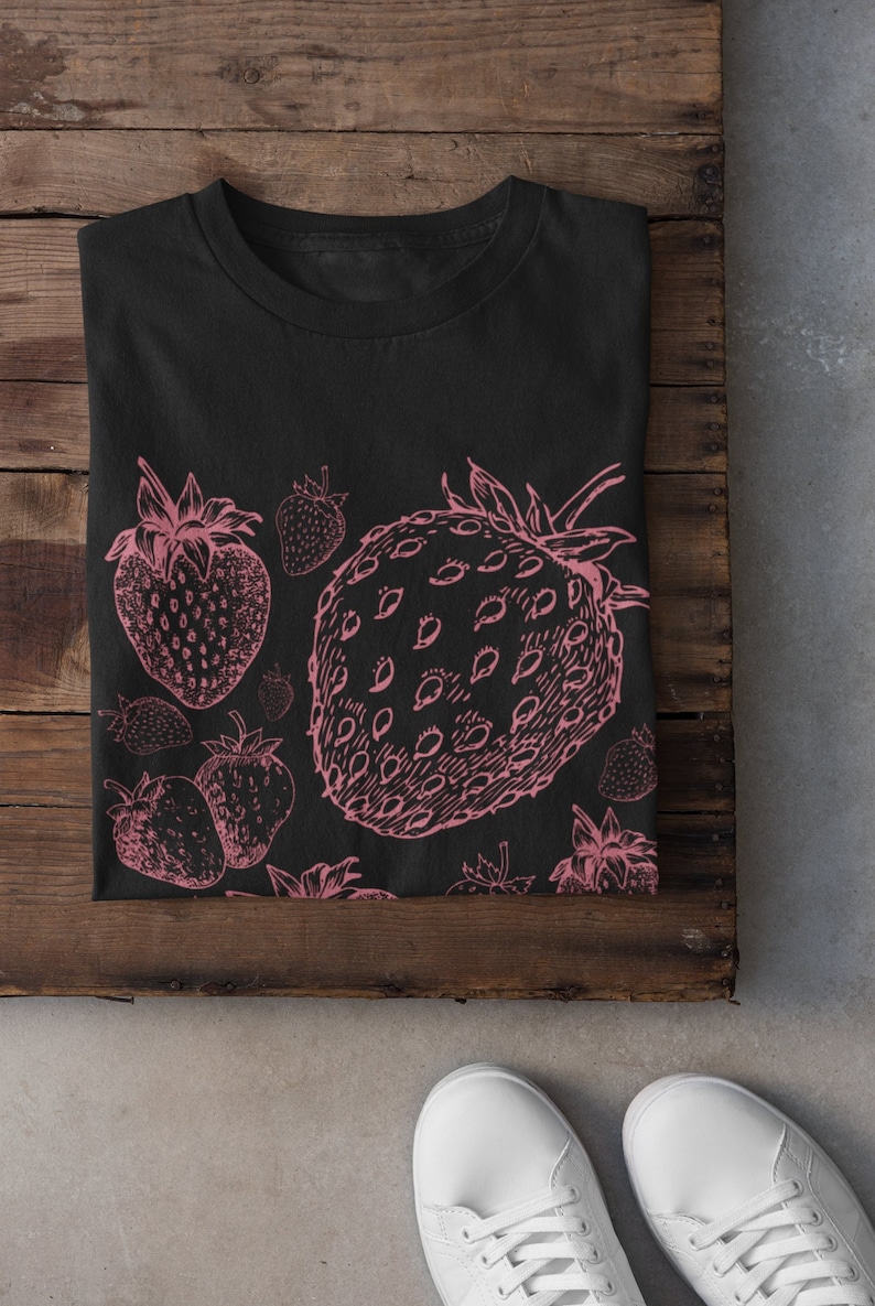 May include: Black t-shirt with a pink strawberry print. The print features multiple strawberries in various sizes and positions.