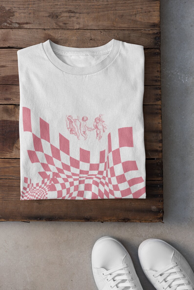 May include: White t-shirt featuring a pink checkered pattern and three cherubs in the centre.
