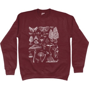 Pode incluir: Uma camisola de cor vinho com uma estampa branca de v&aacute;rios cogumelos, borboletas e outros insetos. A estampa &eacute; uma ilustra&ccedil;&atilde;o de estilo vintage.
