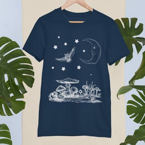 May include: A navy blue t-shirt with a white graphic of a crescent moon, an owl flying, and mushrooms. The graphic is reminiscent of a vintage illustration.