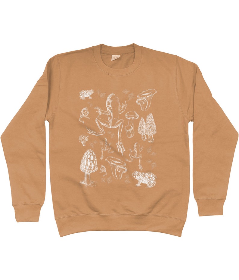 May include: A tan long-sleeve sweatshirt with a white graphic print of frogs and mushrooms.