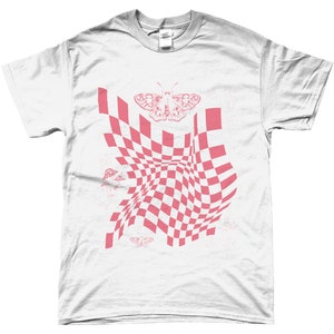 May include: White t-shirt with a pink checkered pattern that appears to be warping or folding. A pink butterfly is centered above the pattern. There are smaller pink butterflies and mushroom shapes scattered around the pattern.