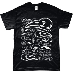 Op de afbeelding: Zwart T-shirt met een witte grafische afbeelding van vogel schedels en botfragmenten. Het ontwerp wordt herhaald over de voorkant. Het shirt heeft korte mouwen en een ronde hals.