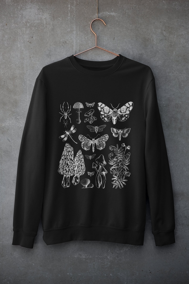 K&ouml;nnte beinhalten: Schwarzer Pullover mit einem wei&szlig;en Grafikdruck verschiedener Insekten, Pilze und Pflanzen. Das Design beinhaltet eine Spinne, eine Libelle, Motten und Pilze.