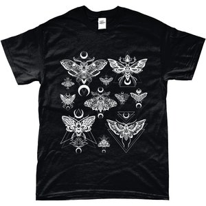 May include: Black t-shirt with a white graphic print of moths and geometric shapes. The moths are stylized and have intricate details. The geometric shapes are triangles and crescents.