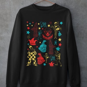 May include: Black sweatshirt with a colorful pattern of clowns, stars, and jester hats.