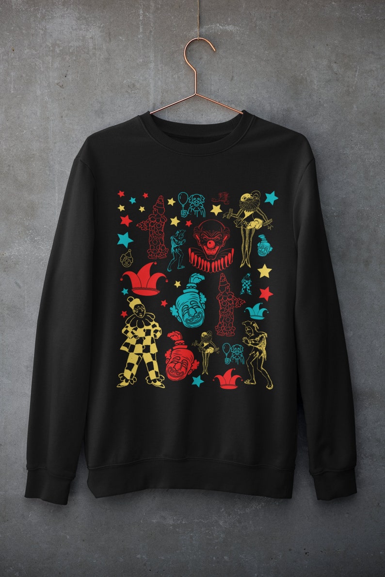 May include: Black sweatshirt with a colorful pattern of clowns, stars, and jester hats.