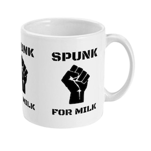 May include: White ceramic mug with a black fist graphic and the words "SPUNK FOR MILK" printed on it. The mug has a curved handle and a cylindrical shape. The text and graphic are repeated around the mug.