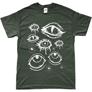 May include: A dark green t-shirt with a white graphic print of multiple stylized eyes. The eyes are drawn in a variety of shapes and sizes, some with dripping tears.