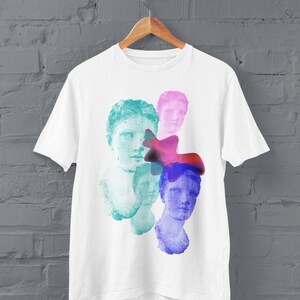 May include: White t-shirt with a colorful graphic print of four faces. The faces are partially obscured by abstract shapes in shades of pink, blue, and purple.