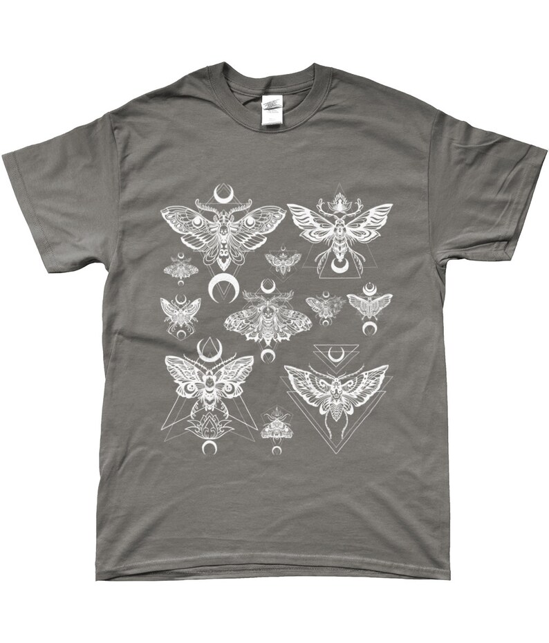 May include: A charcoal grey t-shirt with a white graphic print of moths and geometric shapes. The moths are stylized and have intricate details. The geometric shapes are triangles and crescents.