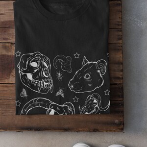 May include: Black t-shirt with a white graphic design featuring animal skulls, stars, and insects.