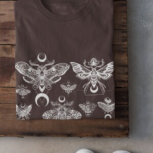 May include: A brown t-shirt with a white print of moths and crescent moons. The print is a repeating pattern of moths and moons.