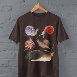 May include: A brown t-shirt with a watercolor design of five snails. The snails are in various shades of brown, orange, purple, and white.