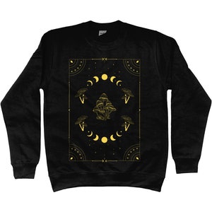 May include: Black sweatshirt with a gold graphic design featuring mushrooms, moons, and stars within a geometric frame.