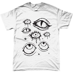May include: White t-shirt with a black and white graphic print of multiple stylized eyes. The eyes are drawn in a variety of shapes and sizes, some with dripping tears.