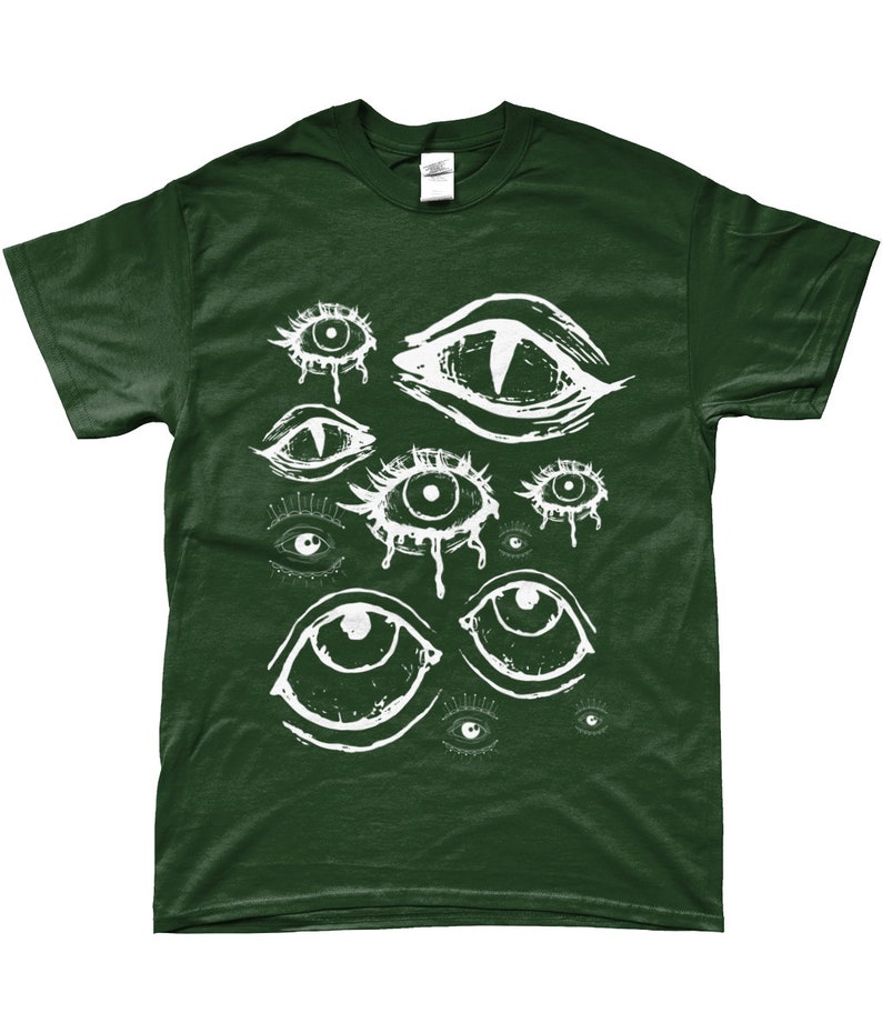 May include: A dark green t-shirt with a white graphic print of multiple stylized eyes. The eyes are drawn in a creepy, abstract style.