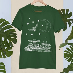 May include: A dark green t-shirt with a white graphic of a crescent moon, a flying owl, and mushrooms. The graphic is in a vintage style.