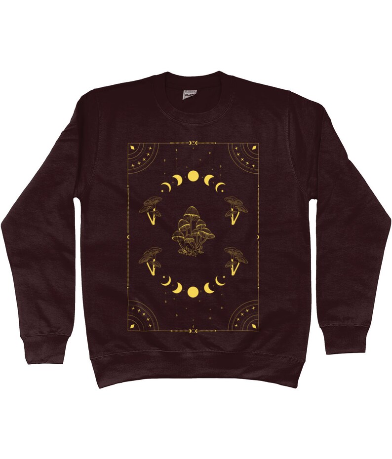 May include: A maroon sweatshirt with a gold graphic design featuring mushrooms, moons, and stars. The design is framed by a geometric border.