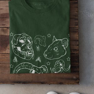 May include: A dark green t-shirt with a white graphic print of animal skulls, insects, and stars.