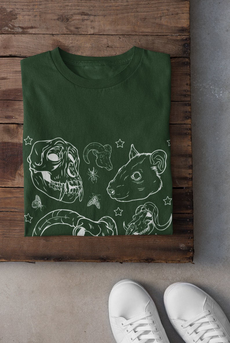 May include: A dark green t-shirt with a white graphic print of animal skulls, insects, and stars.