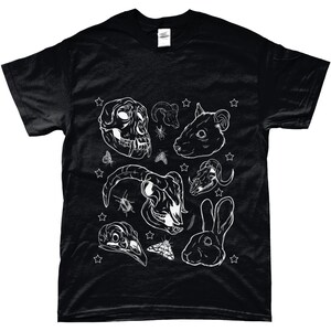May include: Black t-shirt with a white graphic print of various animal skulls, insects, and a rabbit. The design includes a monkey skull, a ram skull, a rat skull, a deer skull, a bird skull, and a rabbit. The design is surrounded by white stars.