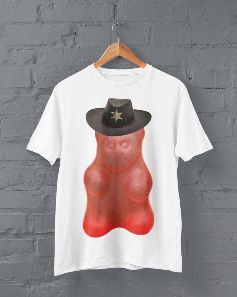 May include: White t-shirt with a red gummy bear wearing a black sheriff's hat with a gold star.