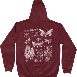 May include: Burgundy hooded sweatshirt with a white print of various insects, mushrooms, and plants. The print includes a spider, dragonfly, butterflies, moths, and mushrooms.