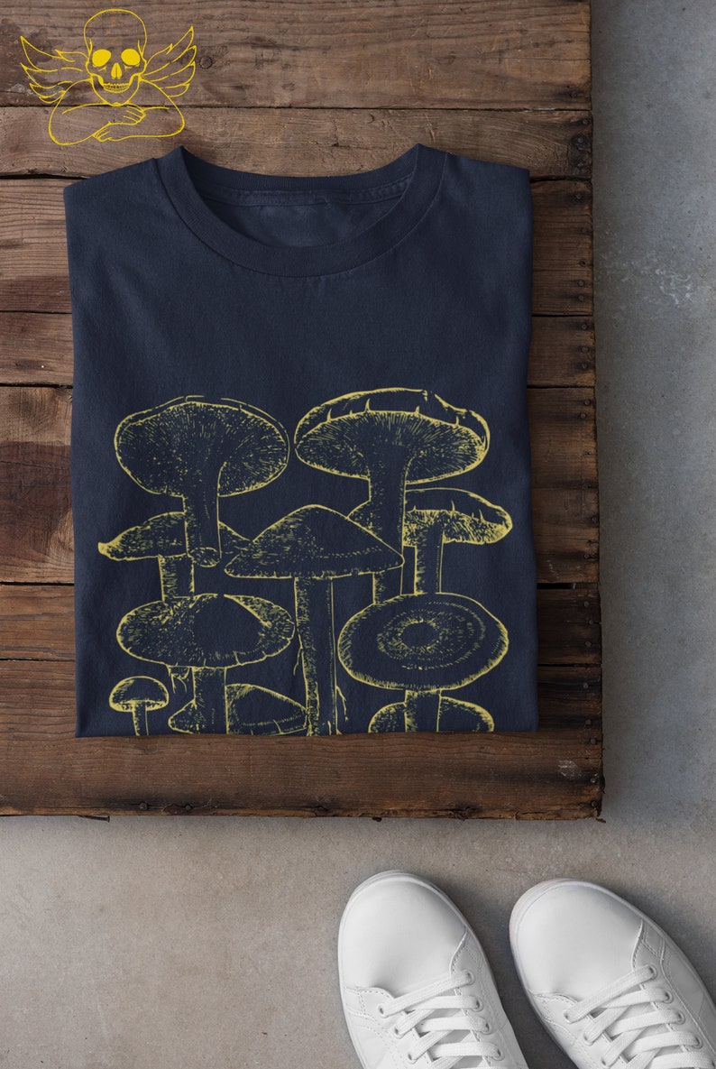 Pode incluir: Uma camiseta azul marinho com um gr&aacute;fico amarelo de um grupo de cogumelos.