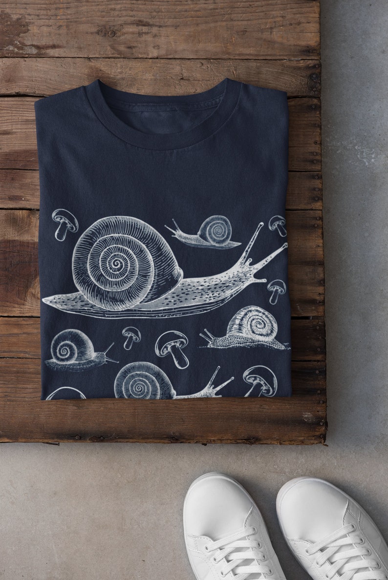 May include: A navy blue t-shirt with a white graphic print of snails and mushrooms.