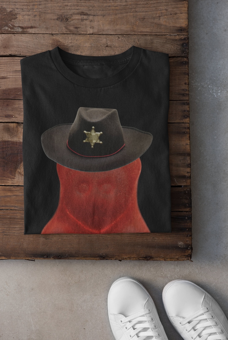 May include: A black t-shirt with a red and brown illustration of a sheriff's hat with a star badge.