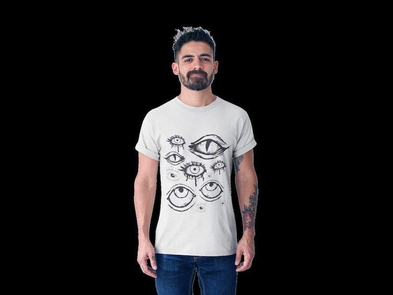 May include: A white t-shirt with a black and white graphic print of multiple eyes. The eyes are drawn in a stylized, abstract style.