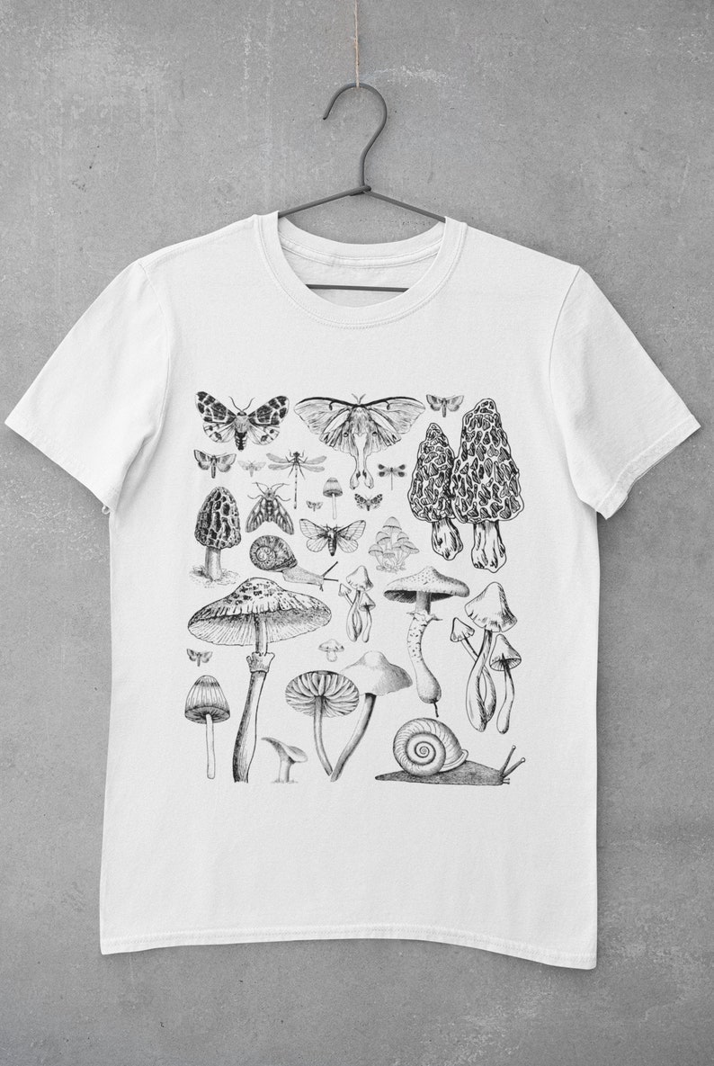 Puede incluir: Camiseta blanca con una ilustraci&oacute;n en blanco y negro de setas, mariposas y un caracol.