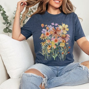 May include: A navy blue t-shirt with a colorful floral print. The flowers are in shades of yellow, orange, pink, and purple. The print is centered on the shirt and covers most of the front.