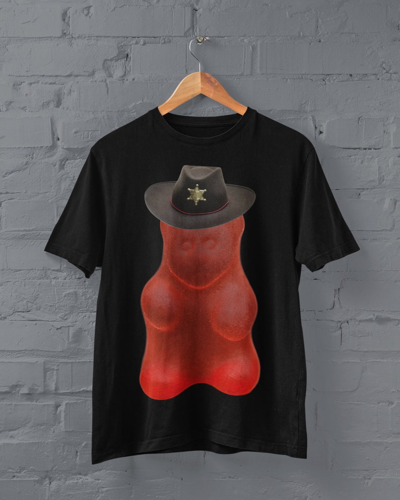 May include: A black t-shirt with a red gummy bear wearing a sheriff's hat. The hat has a gold star badge.