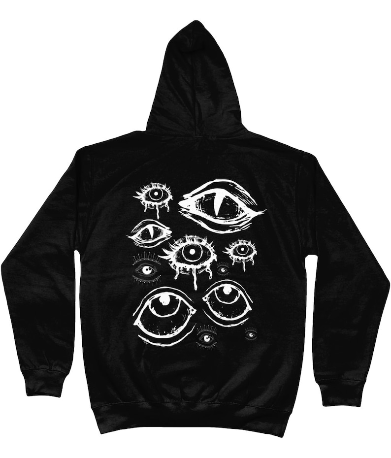 May include: Black hooded sweatshirt with a white graphic print of multiple stylized eyes. The eyes are drawn in a variety of styles, some with tears, some with pupils, and some with a more abstract design.