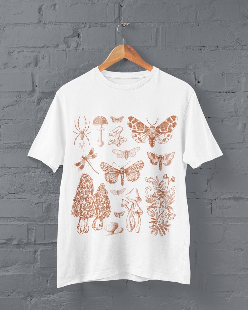 May include: White t-shirt featuring a brown print of various insects and mushrooms. The print includes butterflies, moths, a spider, a dragonfly, and mushrooms.