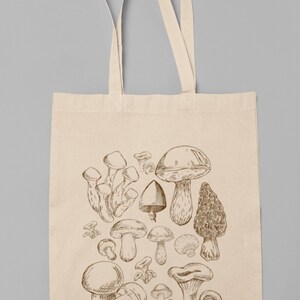 Peut inclure: Un sac fourre-tout en toile beige avec un motif de diff&eacute;rents types de champignons &agrave; l'encre brune. Les champignons sont dessin&eacute;s dans un style vintage.