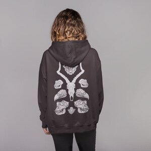 May include: A black hooded sweatshirt with a white graphic print of animal skulls on the back.