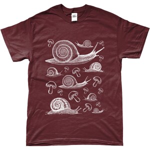 May include: A maroon t-shirt with a white graphic print of snails and mushrooms. The snails are of varying sizes and are depicted in a vintage style.