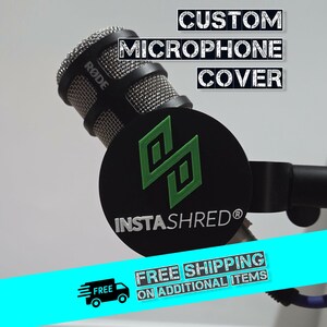 May include: A black microphone with a silver mesh head and a custom cover. The cover is black with a green logo and the text "INSTASHRED®". The words "CUSTOM MICROPHONE COVER" are displayed above the microphone.