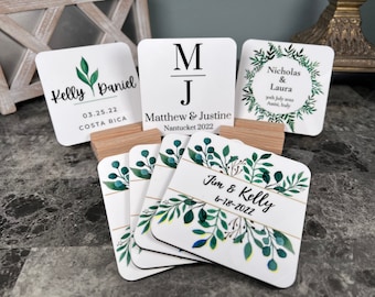 May include: Set of six white square coasters with a green leafy design and gold accents. The coasters feature the names "Kelly Daniel", "Matthew & Justine", "Nicholas & Laura", and "Jim & Kelly" with corresponding dates.