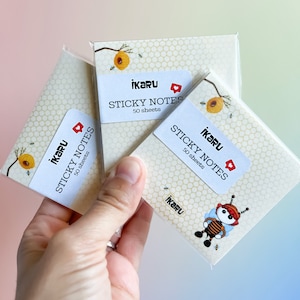 May include: Three packs of sticky notes with a honeycomb pattern and bee illustrations. Each pack has a label that says "IKARU STICKY NOTES 50 sheets".