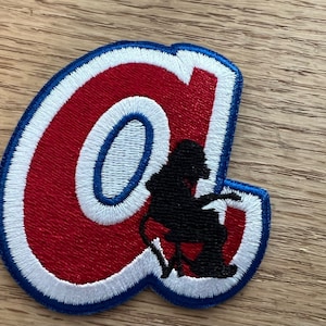 May include: A red, white, and blue embroidered patch with the letter "A" and a silhouette of a person sitting in a chair.