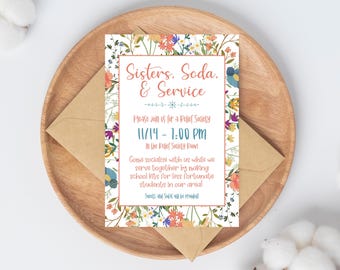 May include: A floral invitation with the text "Sisters, Soda, & Service" is displayed on a wooden plate with a brown envelope. The invitation includes details for a Relief Society event on 11/14 from 1:00 PM. The invitation is decorated with colorful flowers.