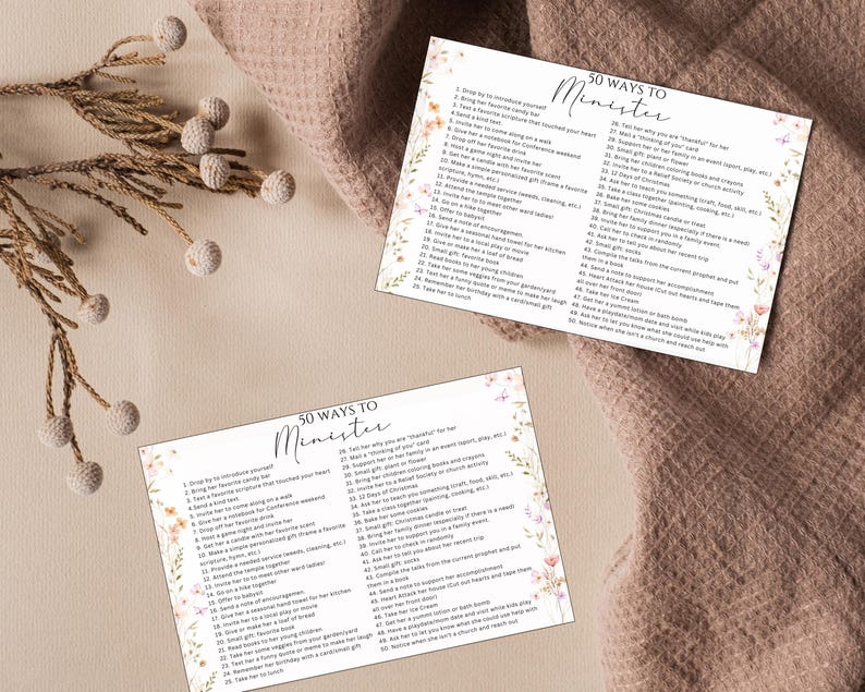 May include: Two cards with the text "50 Ways to Minister" in elegant script, surrounded by floral and butterfly illustrations. The cards are on a textured, neutral-toned surface, with a sprig of decorative elements in the upper left corner.