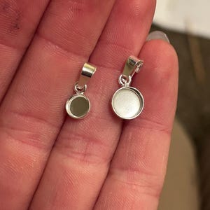 May include: Two silver pendant blanks with round bezels. The larger bezel is approximately 1 inch in diameter and the smaller bezel is approximately 3/4 inch in diameter.