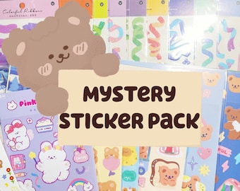 May include: A mystery sticker pack with a variety of cute cartoon bears, animals, and other designs. The stickers are on sheets of paper with a light blue, pink, and yellow background. The text "MYSTERY STICKER PACK" is written in brown letters on a beige background.