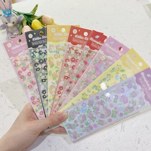 May include: A set of eight sticker sheets featuring floral designs with glitter accents. The sheets are labelled with the text "Little Da" and "Bouquet of" with the words "Spring Field" and "Spring Field Flowers" repeated on each sheet.